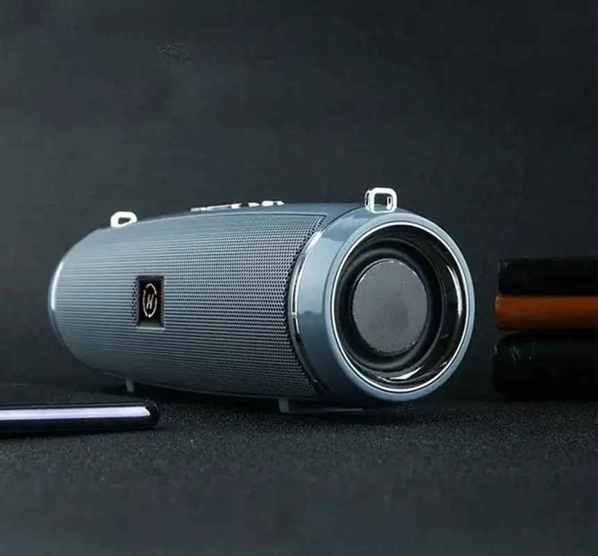 Portable waterproof Bluetooth speaker in gray with deep bass design, shown on a tabletop for camping, outdoor travel, and backyard use