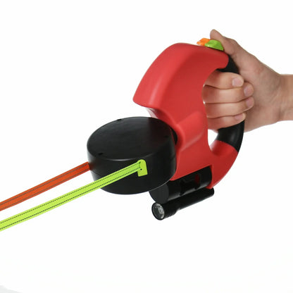 Hand holding red dual retractable dog leash with ergonomic grip, reflective cords, and built-in flashlight