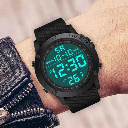Digital adventure watch worn on a wrist, featuring a rugged black case, textured silicone strap, and bright teal backlit digital display showing time, date, and alarm indicators.